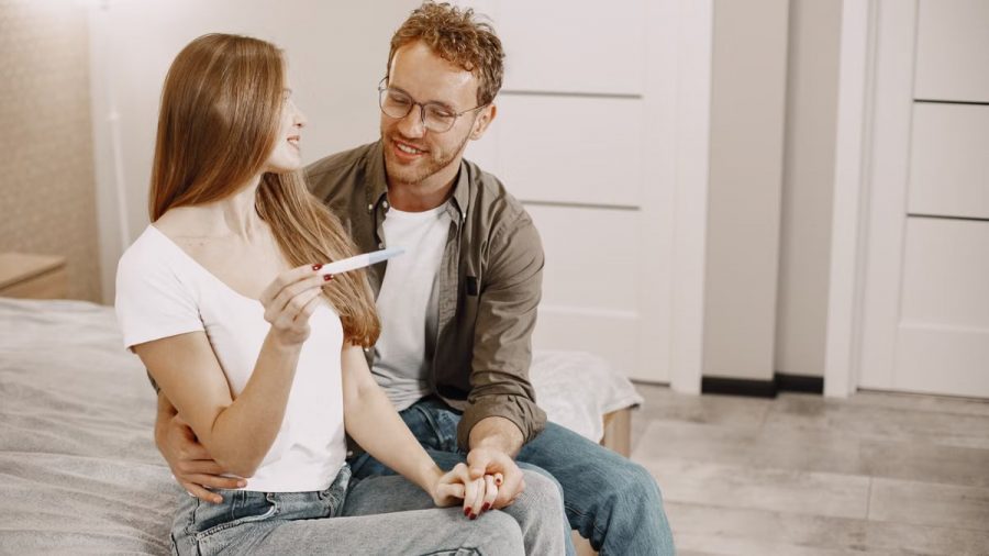 Joyful couple checking a pregnancy test together in a cozy room, celebrating good news.